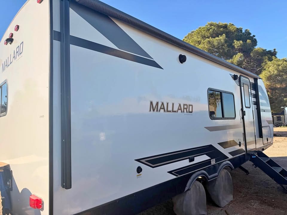 White Mallard RV parked under clear sky.