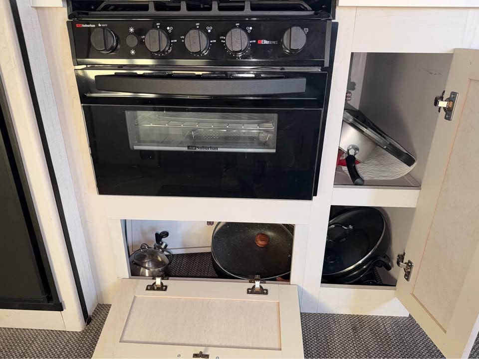 Black kitchen stove with open storage cabinets.