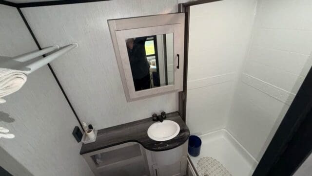 Compact modern bathroom with shower and sink.