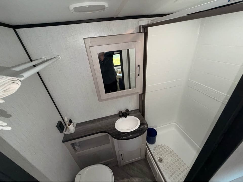 Compact modern bathroom with shower and sink.