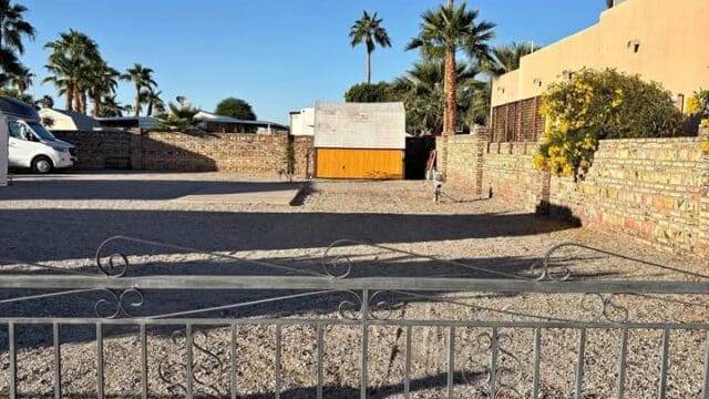 Gated yard with palm trees and van.