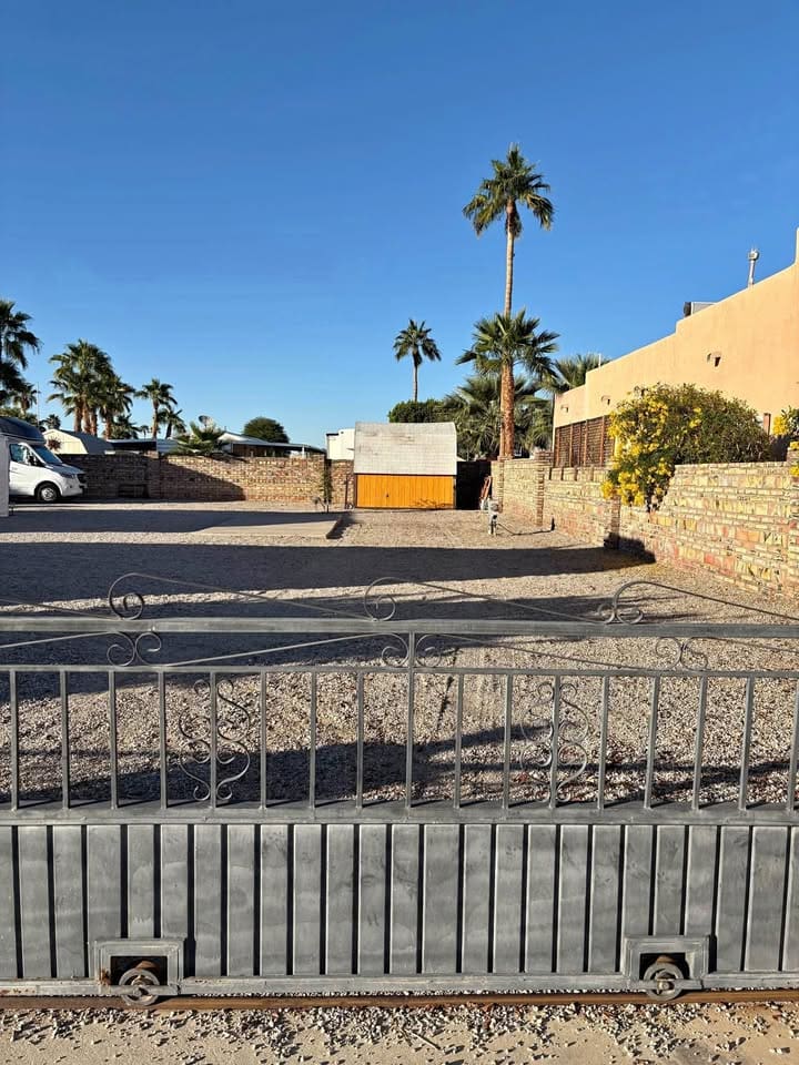 Gated yard with palm trees and van.