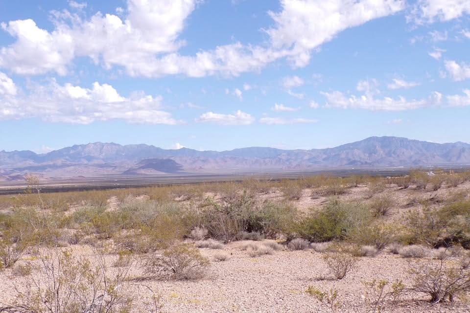 Desert landscape with mountains and cloudy sky.
